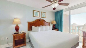 Una camera d'albergo con un letto grande, due comodini, un ventilatore a soffitto e vista sull'esterno.