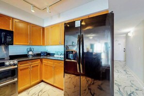 Une cuisine avec des meubles en bois, un réfrigérateur en acier inoxydable, un four à micro-ondes et une cuisinière.