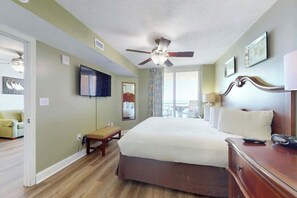 Ein Hotelzimmer mit Bett, Schreibtisch, Stuhl, Fernseher und Deckenventilator.