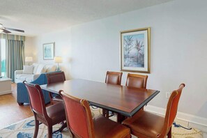 A dining area with a rectangular table and six chairs, a sofa, and a ceiling fan. - Bahama Sands Unit 1207 (North Myrtle Beach)