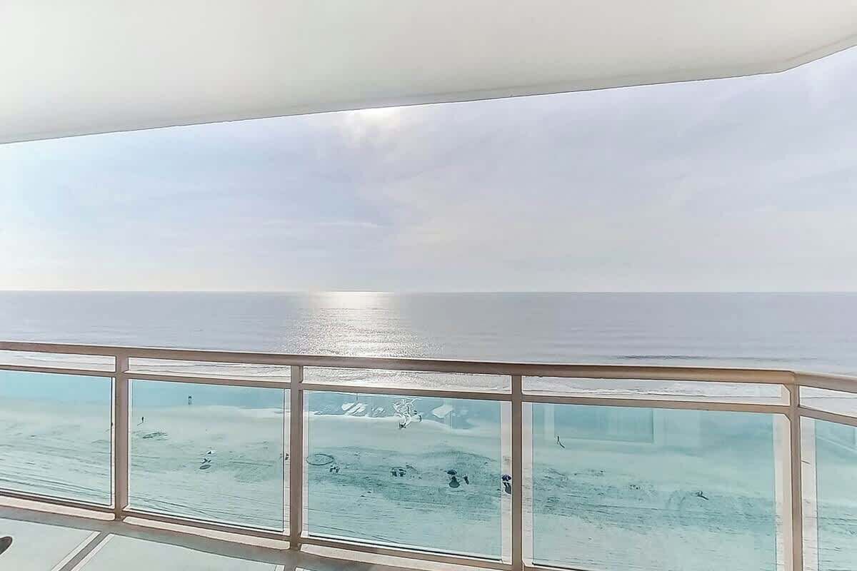 Vista desde un balcón, cielo despejado y mar tranquilo.
