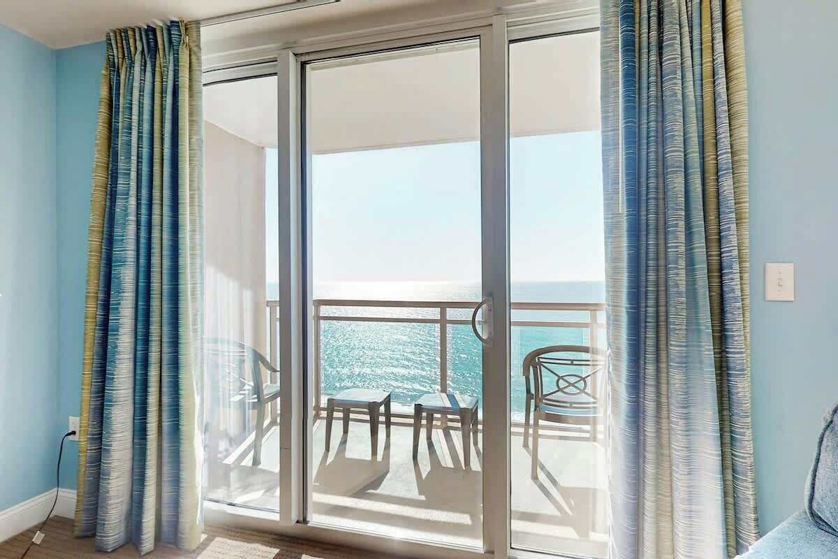 Een kamer met een schuifdeur naar een balkon met uitzicht op zee.