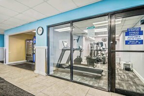 A fitness center with a treadmill, weight machines, and a sign indicating availability from 7 am to 11 pm. - Ocean Park Resort 1222/1224 Combo (Myrtle Beach)