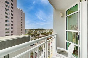 A balcony with a view of a cityscape, including a tall building and a road with vehicles. - Carolinian Beach Resort 0734 (Myrtle Beach)