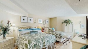 Un dormitorio con una cama grande, mesitas de noche, un aparador y un televisor.