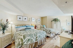 Ein Schlafzimmer mit einem großen Bett, Nachttischen, einer Kommode und einem Fernseher.