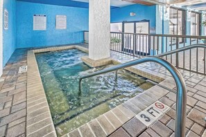 An indoor hot tub area with clear water, a metal railing, and a blue wall with informational signs. - Ocean Park Resort 0522/0524 Combo (Myrtle Beach)