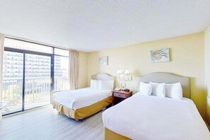 Ein Hotelzimmer mit zwei Betten, einem großen Fenster mit Blick auf Gebäude und einem Balkon.