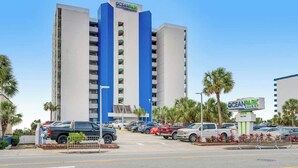 A hotel with a prominent blue and white facade, multiple parking spaces, and a clear sky. - Ocean Park Resort 0322/0324 Combo (Myrtle Beach)