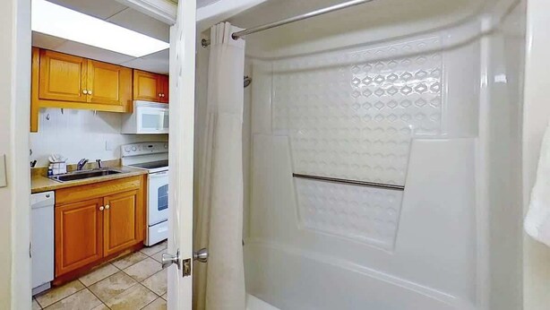 A kitchen with wooden cabinets, a white stove, and a white microwave. - Ocean Park Resort 0322/0324 Combo (Myrtle Beach)