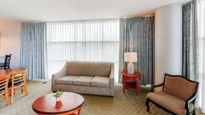 A hotel room with a sofa, a round table, a lamp, and a chair. - Sandy Beach Resort 504 (Myrtle Beach)