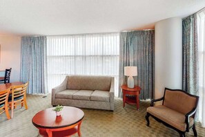 A hotel room with a sofa, a round table, a lamp, and a chair. - Sandy Beach Resort 504 (Myrtle Beach)