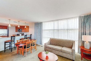 A compact hotel room with a kitchenette, dining area, and a sofa. - Coastal Luxe | Sandy Beach Five Oh Four (Myrtle Beach)