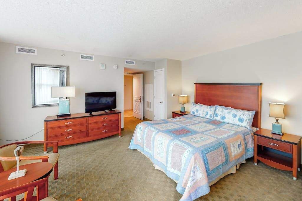 A hotel room with a bed, a television, a desk, and a chair.