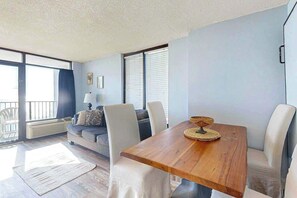 Una sala de estar con una mesa de comedor de madera, un sofá y una ventana con persianas.