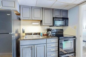 A kitchen with grey cabinets, a stainless steel refrigerator, a microwave, a coffee maker, and a double oven. - Ocean Park Resort 0922/0924 Combo (Myrtle Beach)
