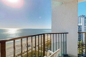 Uma varanda com vista para o mar e um edifício ao fundo.