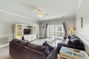Ein Wohnzimmer mit einer Couch, einem Fernseher und einem Glastisch.