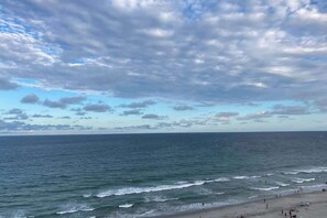 Ein Strand mit Wellen und einem bewölkten Himmel.