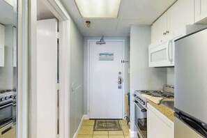 Eine kleine Küche mit einem weißen Kühlschrank, Herd und einer Mikrowelle.