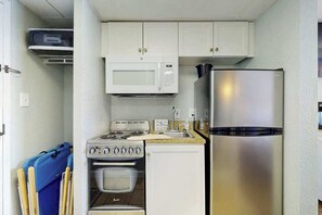 A compact kitchenette with a microwave, stove, oven, and refrigerator. - Pelicans Flight at Sandcastle South (Myrtle Beach)