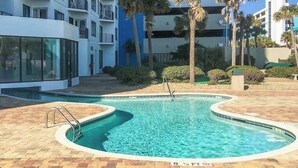A swimming pool with a curved edge, surrounded by a brick patio. - Palace Resort Unit 1508 (Myrtle Beach)