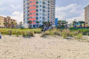 Ein Hotel direkt am Strand mit mehreren hohen Gebäuden, einem Sandstrand und etwas Vegetation.