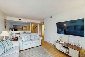 Uma sala de estar moderna com sofá, televisão de tela plana na parede e um rack de madeira para entretenimento.