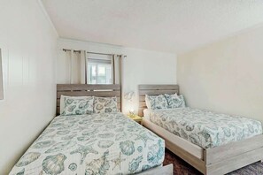 Ein Schlafzimmer mit zwei Betten, jeweils mit einem hölzernen Kopfende und passender Bettwäsche.