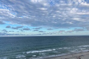 A beach with waves, people, and a cloudy sky. - Sandcastle South 1509 (Myrtle Beach)