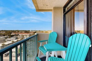 A balcony with two chairs and a table, overlooking a residential area with houses and a road. - Sandtrap at the Verandas (North Myrtle Beach)