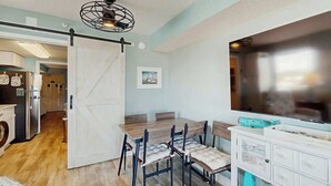 Un comedor con una mesa y sillas de madera, un mueble blanco con cajones y un ventilador de techo.