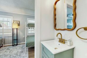 A bathroom with a white sink, gold faucet, and a mirror with a gold frame. - Coastal Retreat on Bay Street (North Myrtle Beach)