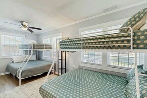 A room with bunk beds, a ceiling fan, and large windows. - Coastal Retreat on Bay Street (North Myrtle Beach)
