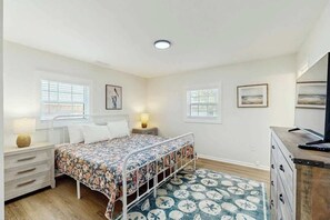 A bedroom with a bed, bedside tables, a dresser, and a television. - Coastal Retreat on Bay Street (North Myrtle Beach)