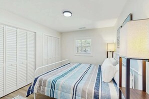 Ein Schlafzimmer mit einem Bett, einem Nachttisch, einer Lampe und einem Fenster.