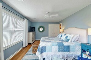 A bedroom with a bed, a ceiling fan, a dresser, a television, and a window with blinds. - Shorehaven Unit W-2 Condo (North Myrtle Beach)