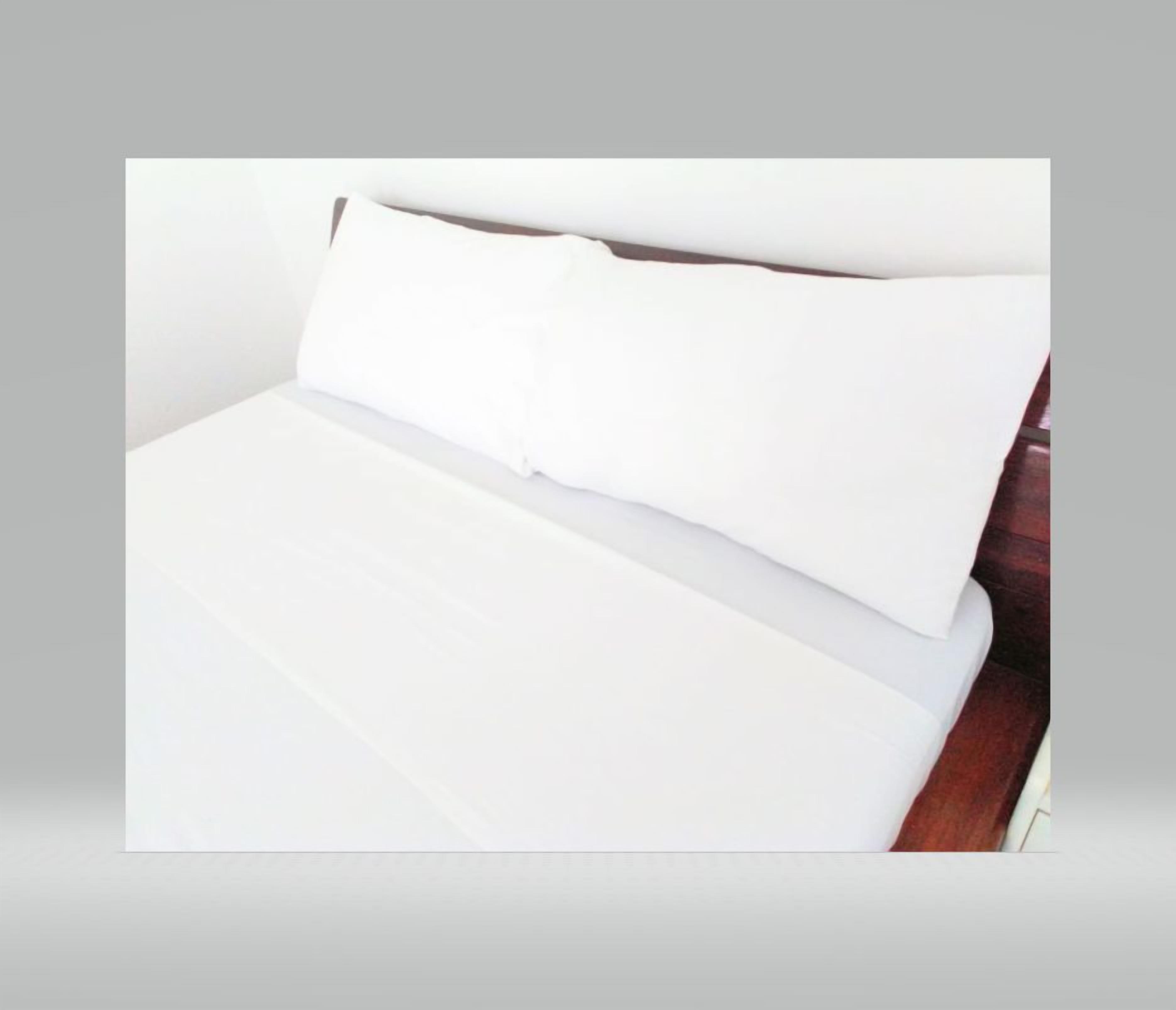 Una cama con ropa de cama blanca y un cabecero de madera.