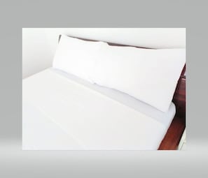 Un lit avec une literie blanche et une tête de lit en bois.