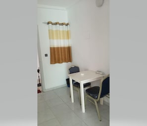 A small room with a white table, two chairs, and a striped curtain.