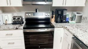 A kitchen with a stainless steel stove, a toaster, a coffee maker, and a dishwasher. - River Oaks Unit 25A Condo (Myrtle Beach)