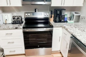 A kitchen with a stainless steel stove, a toaster, a coffee maker, and a dishwasher. - River Oaks Unit 25A Condo (Myrtle Beach)