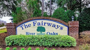 A sign with the text 'The Fairways River Oaks' surrounded by greenery and brick pillars. - River Oaks Unit 25A Condo (Myrtle Beach)