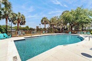 A swimming pool with lounge chairs and palm trees. - Lakefront Retreat at Litchfield by the Sea (Pawleys Island)