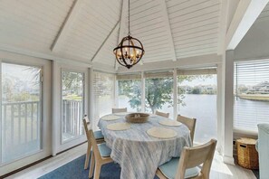 A dining area with a round table, chairs, and a hanging light fixture. - Lakefront Retreat at Litchfield by the Sea (Pawleys Island)