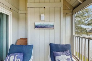 A porch with two blue cushioned chairs, a welcome sign, and a view of a body of water. - Lakefront Retreat at Litchfield by the Sea (Pawleys Island)