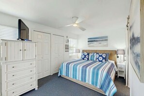Ein Schlafzimmer mit einem Bett, einem Kleiderschrank, einem Deckenventilator und einem Bild an der Wand.