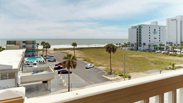 Um hotel com vista para o oceano, área de estacionamento e um edifício com uma placa.