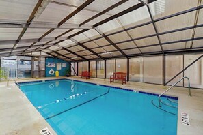 An indoor swimming pool with clear lane markings, benches, and a covered roof structure. - La Mirage Unit 402 Condo (Myrtle Beach)