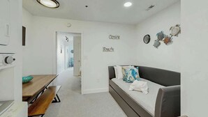 Uma sala de estar moderna com um sofá, uma mesa de jantar e uma cozinha equipada com micro-ondas.